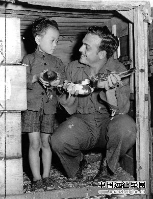 一名美国士兵和一名中国孩子一起摆弄鸽子。